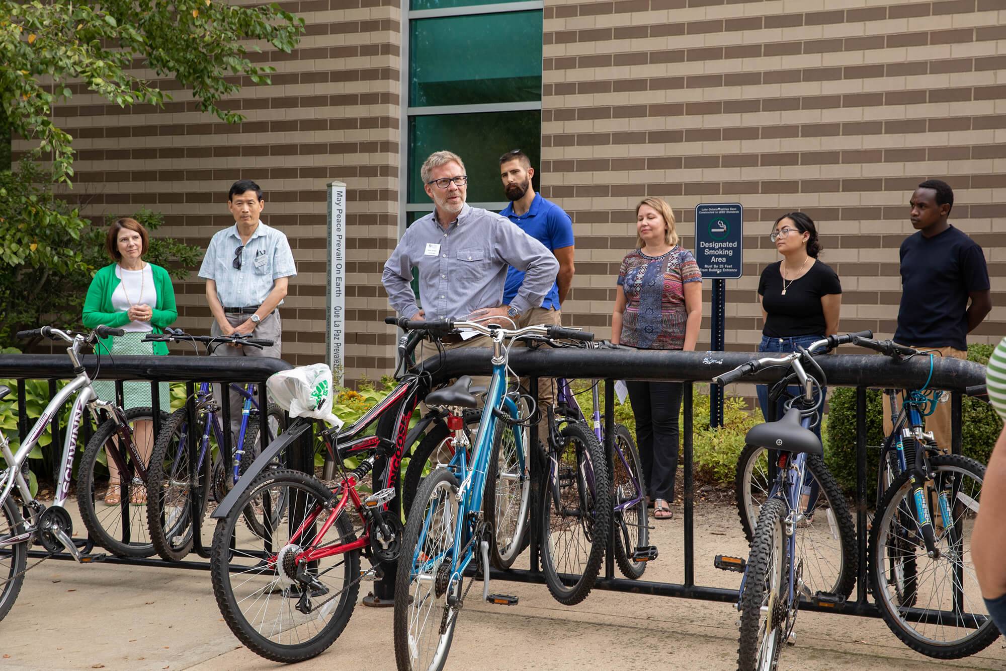 Brooks College Interim Dean Mark Schaub speaks to a small crowd around the peace pole outside Lake Ontario Hall